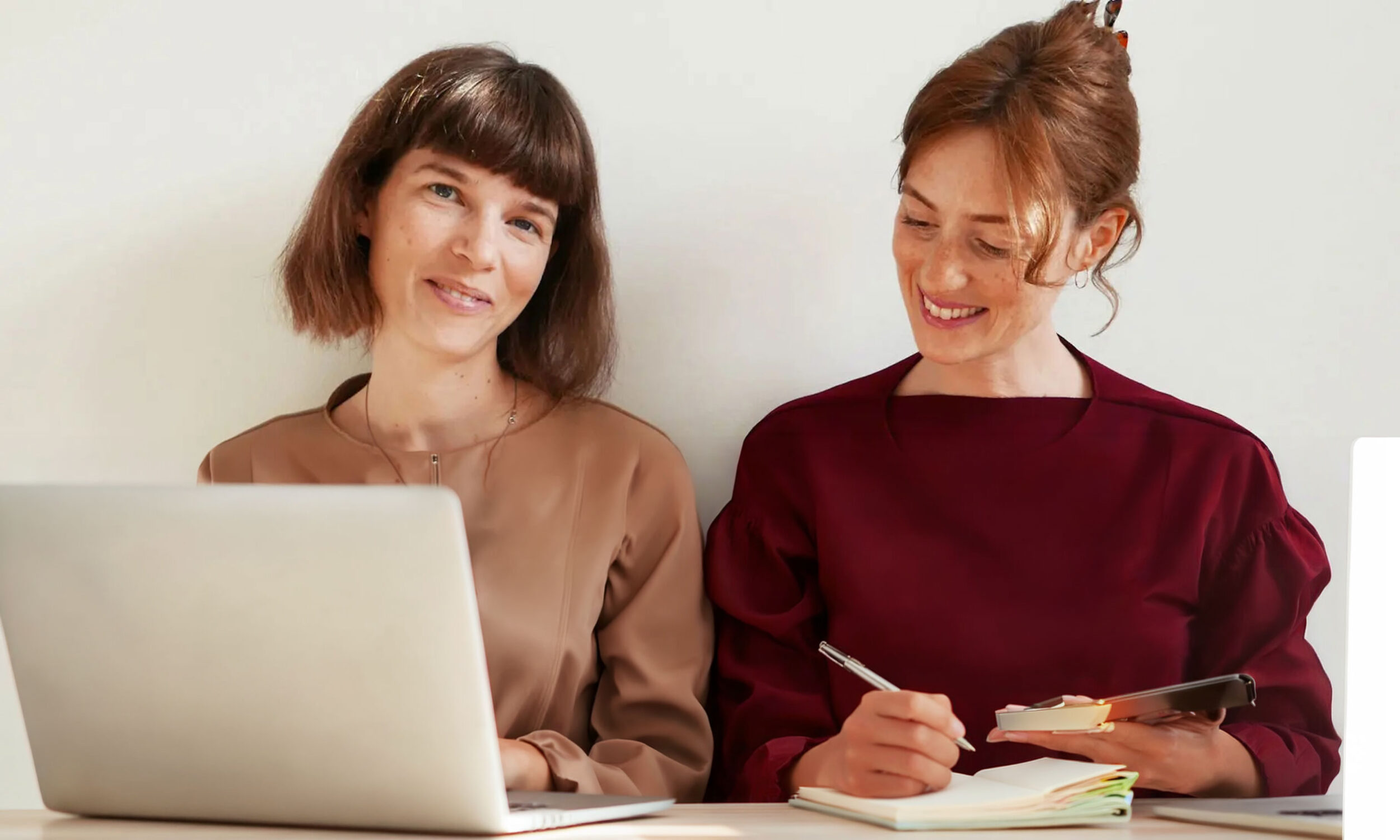 To yngre kvinder der sidder og arbejder på en laptop