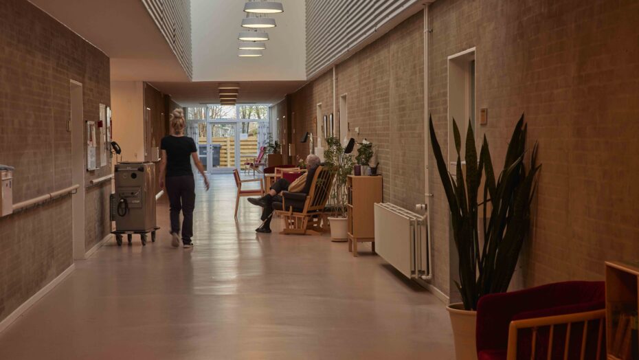 en gang på et plejehjem, hvor der sidder en borger og en medhjælper