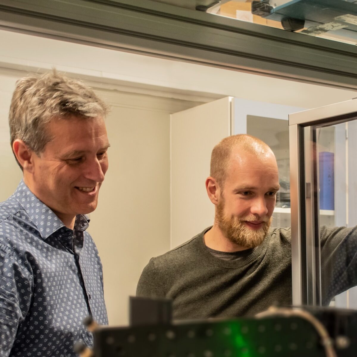 to forskere der står og kigger ind ad et vindue